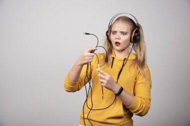 Kulaklıklı sarışın kadın kablolara bakıyor. Yüksek kalite fotoğraf