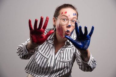 Yüzünde boya ve gri arka planda gözlük olan bir kadın. 