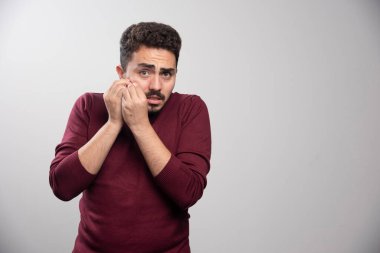 Gri duvardan korkan esmer bir adam. Yüksek kalite fotoğraf