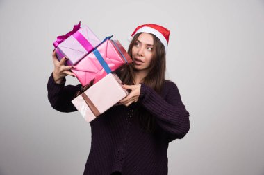 Noel Baba 'nın şapkalı genç kadın elinde yaylı Noel hediyeleri tutuyor. Yüksek kalite fotoğraf