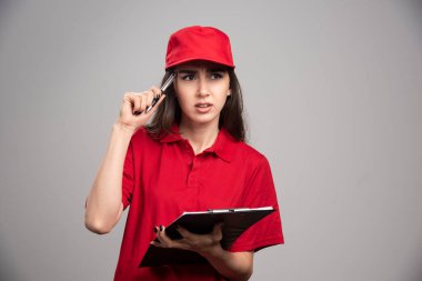 Kırmızı üniformalı kadın gri arka planda poz veriyor. Yüksek kalite fotoğraf