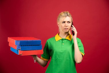 Teslimatçı kadın telefonda konuşurken elinde iki fincan kahve tutuyor. Yüksek kalite fotoğraf