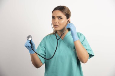 Beyaz arka planda steteskobu olan genç bayan hemşire.