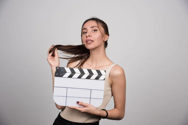Brunette Perempuan Memegang Clapperboard Dan Bermain Dengan Rambutnya Foto Berkualitas — Stok Foto