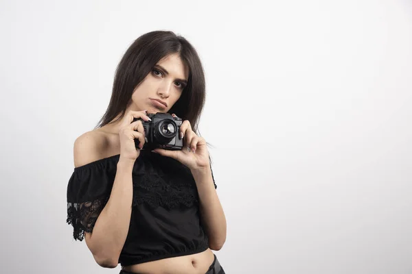 ブルネットの女性は白い背景にカメラで写真を撮る 高品質の写真 — ストック写真