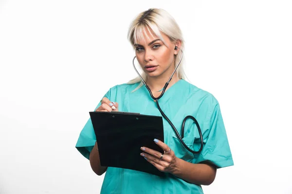 白い背景にクリップボードに何かを書いている女性医師 高品質の写真 — ストック写真