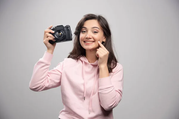 Kobieta Fotograf Trzyma Kamerę Szczypie Się Policzek Wysokiej Jakości Zdjęcie — Zdjęcie stockowe