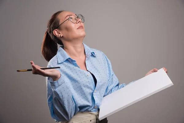 Frau Mit Leerer Leinwand Und Pinsel Auf Grauem Hintergrund — Stockfoto