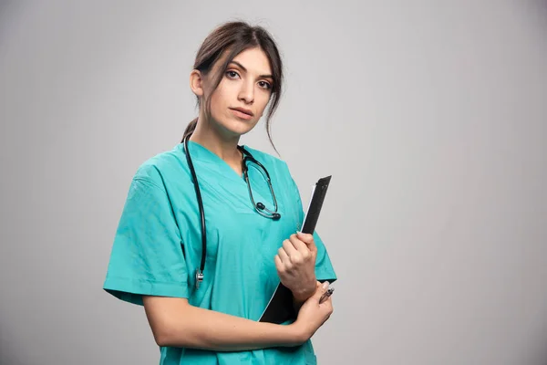 グレーの背景にクリップボードを保持する女性医師 高品質の写真 — ストック写真
