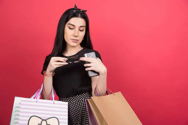 Young Woman Looking Her Glasses Holding Bags Phone Red Background — Stock Photo, Image