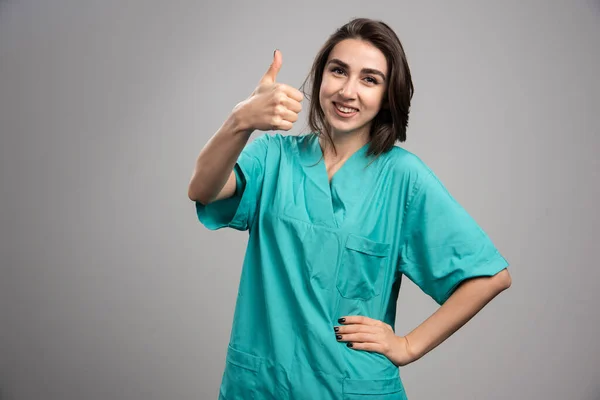 灰色の背景に親指をあげる女性医師 高品質の写真 — ストック写真