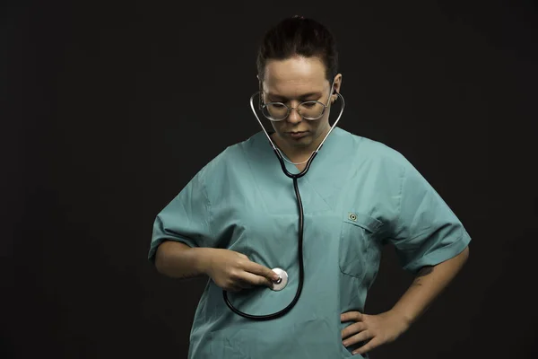 聴診器を持って胃をチェックする緑色の制服の女性医師 高品質の写真 — ストック写真