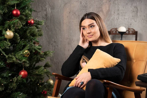 Όμορφη Νεαρή Γυναίκα Κάθεται Δίπλα Στο Χριστουγεννιάτικο Δέντρο Υψηλής Ποιότητας — Φωτογραφία Αρχείου