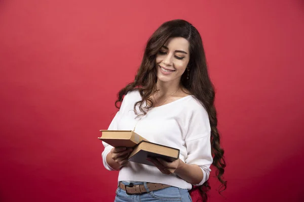 Mujer Morena Mirando Libros Sobre Fondo Rojo Foto Alta Calidad — Foto de Stock