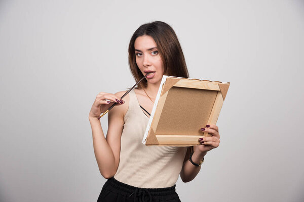 Young woman posing with empty canvas and brush. High quality photo