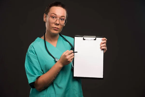 Γυναίκα Νοσοκόμα Πράσινη Στολή Δείχνει Ιστορικό Του Ασθενούς Και Κάνει — Φωτογραφία Αρχείου