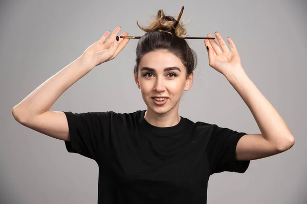 Young woman with messy bun standing on gray background. High quality photo