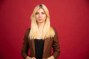 Kırmızı arka planda poz veren kahverengi ceketli bir ofis çalışanı. Yüksek kalite fotoğraf