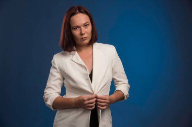 Beyaz ceketli genç kız düğmelerini ilikliyor. Yüksek kalite fotoğraf