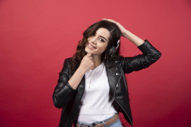 Kulaklık takan ve kırmızı arka planda poz veren genç bir kadın. Yüksek kalite fotoğraf