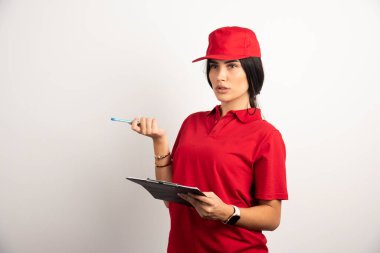 Elinde not panosu olan bir kadın kurye bir şeyler düşünüyor. Yüksek kalite fotoğraf