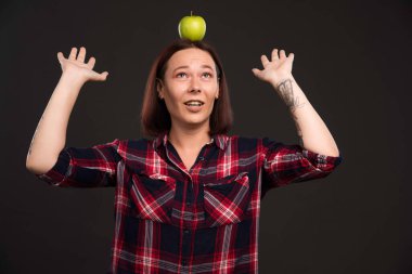 Sonbahar kış koleksiyon giysileri içinde kafasında yeşil bir elma tutan bir kadın model. Yüksek kalite fotoğraf