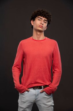 Kırmızı gömlekli genç model ellerini cebine koyarak poz veriyor. Yüksek kalite fotoğraf