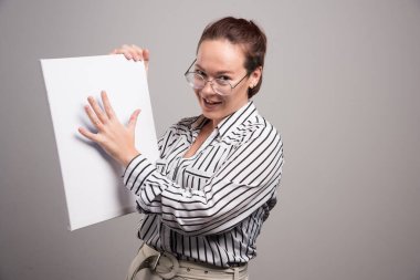 Gri arkaplanda boş beyaz tuvalini gösteren bir kadın 