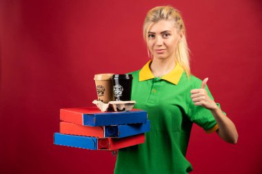 Teslimatçı kadın elinde pizza ve kahve tutarken onay veriyor. Yüksek kalite fotoğraf