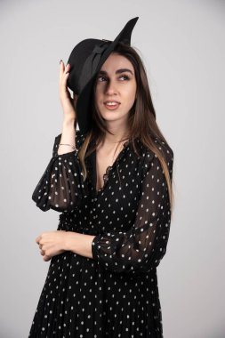 Şapkasını tutan siyah elbiseli genç bir kadın. Yüksek kalite fotoğraf