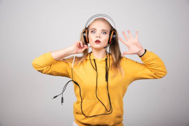 Gri arka planda kulaklıkla poz veren güzel bir kadın. Yüksek kalite fotoğraf