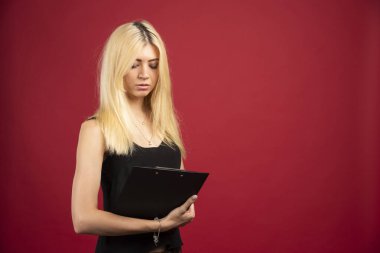 Kırmızı arka planda panoya bakan kadın çalışan. Yüksek kalite fotoğraf