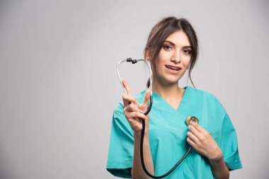 Mutlu doktor gri arka planda steteskop gösteriyor. Yüksek kalite fotoğraf