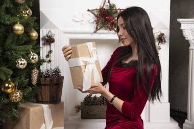 Noel hediyeleri taşıyan kırmızı elbiseli esmer bir kadının fotoğrafı. Yüksek kalite fotoğraf