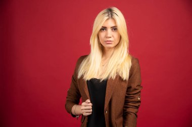 Kırmızı arka planda poz veren kahverengi ceketli bir ofis çalışanı. Yüksek kalite fotoğraf