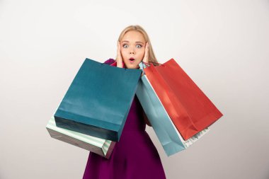 Kulaklarını kapatırken alışveriş torbaları taşıyan şaşırmış bir kadın. Yüksek kalite fotoğraf