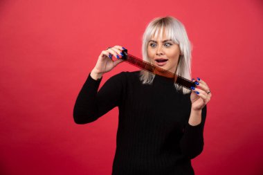 Kırmızı arka planda bir fotoğraf kasetine bakan genç bir kadın. Yüksek kalite fotoğraf