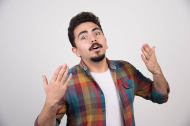 Gri arka planda mavi tişörtlü, şok olmuş genç bir adamın portresi.