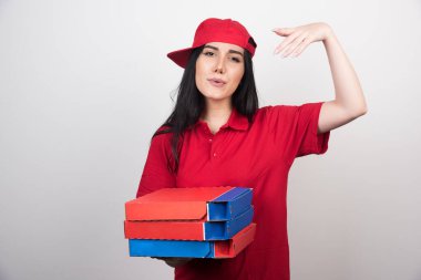 Genç teslimatçı kadın elinde beyaz arka planda üç kutu pizza tutuyor. Yüksek kalite fotoğraf