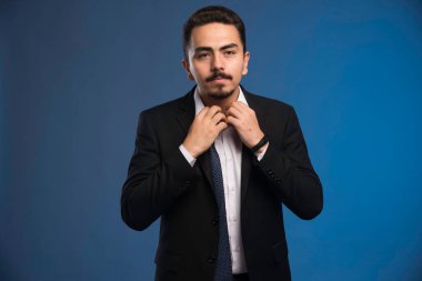 Siyah takım elbiseli bir iş adamı gömleğinin düğmesini açıyor. Yüksek kalite fotoğraf