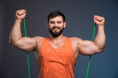 Koyu mavi arka planda spor olsun diye lastik tutan genç adam. Yüksek kalite fotoğraf