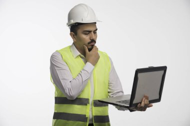 Üniformalı bir mühendis dizüstü bilgisayar tutuyor ve düşünüyor. Yüksek kalite fotoğraf