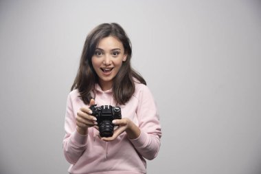 Kamerayla poz veren pembe kazaklı mutlu kadın. Yüksek kalite fotoğraf