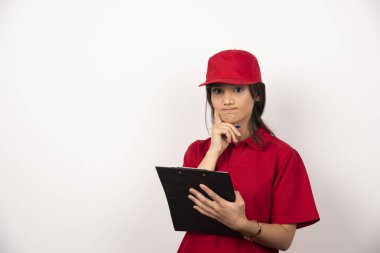 Beyaz arka planda panosu olan kırmızı üniformalı genç teslimatçı kadın. Yüksek kalite fotoğraf