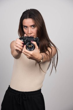 Gri arka planda kamera sunan güzel bir kadın. Yüksek kalite fotoğraf