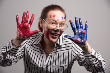 Yüzünde boya ve gri arka planda gözlük olan bir kadın. 