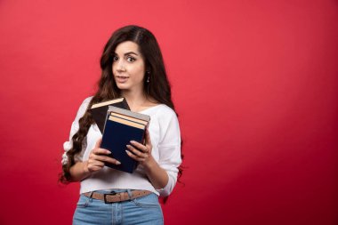 Kırmızı arka planda kitap tutan genç bir kadın model. Yüksek kalite fotoğraf