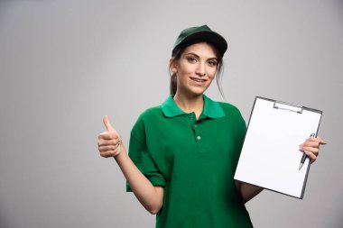 Gri arka planda poz veren teslimatçı kadın. Yüksek kalite fotoğraf