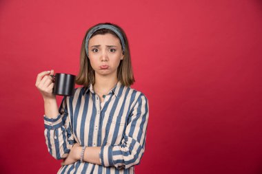 Elinde üzgün bir ifadeyle bir fincan kahve tutan genç bir kadın. Yüksek kalite fotoğraf