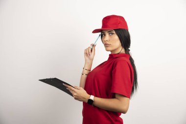 Beyaz arka planda elinde kalem ve not panosuyla duran kadın kurye. Yüksek kalite fotoğraf